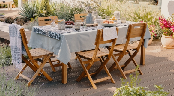 Ein gedeckter Gartentisch steht auf der Terrasse. F&uuml;nf St&uuml;hle sind um den Tisch angeordnet.