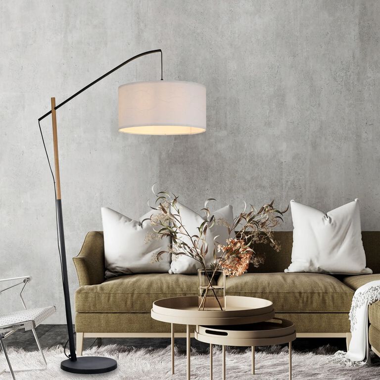 Sofa mit dekorativer Deko und einer modernen Stehleuchte vor einer grauen Betonwand.