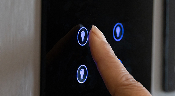 Finger berührt ein modernes Touch-Bedienfeld zur Steuerung der Beleuchtung mit leuchtenden Symbolen.