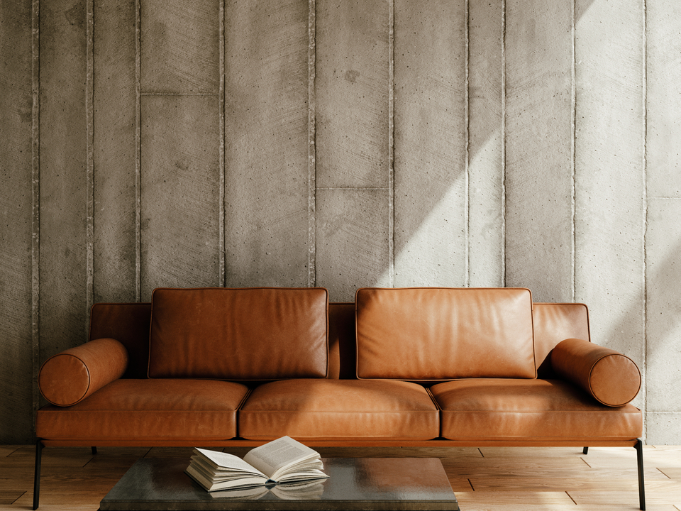 Wohnzimmer im Industrial Look mit Leder-Sofa, Betonstruktur und minimalistischer Einrichtung
